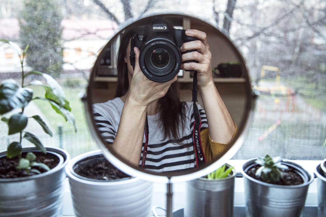 Jente fotograferer seg gjennom et speil